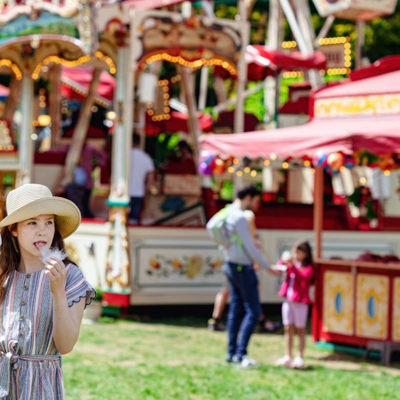 a-girl-in-a-hat-and-a-dress-eating-cotton-candy-on-2023-11-27-05-36-21-utc